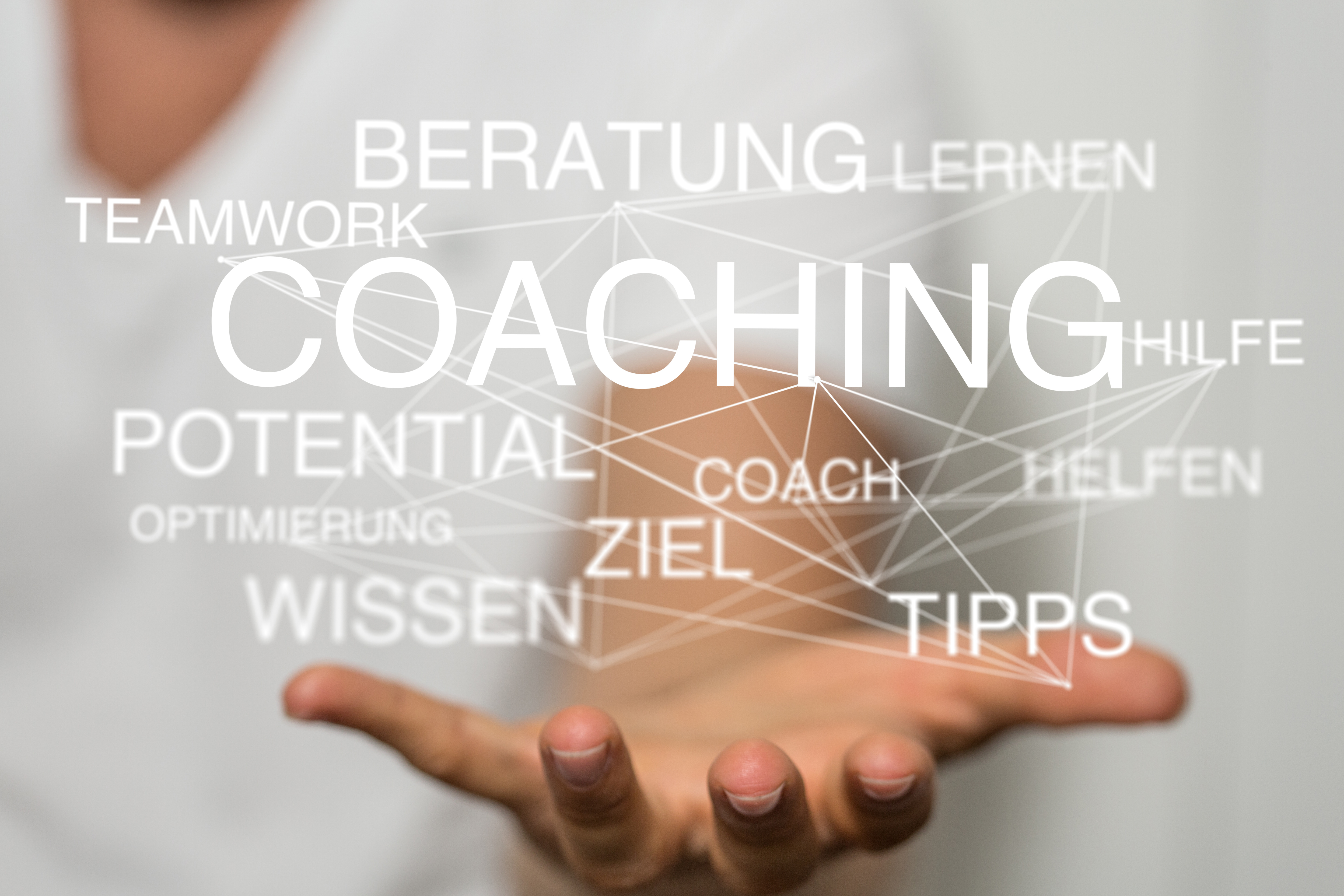 Hände unter einer Wortwolke mit Begriffen rund um Coaching und persönliche Entwicklung